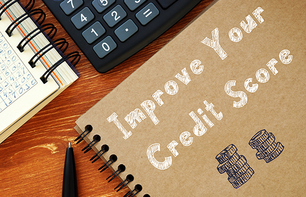 image of calculator and notepad on desk with words "improve your credit score" written on the notepad